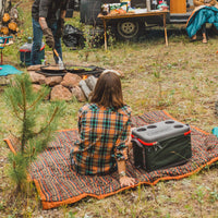 Woman at campsite sitting on Kelty Cordavan Blanket