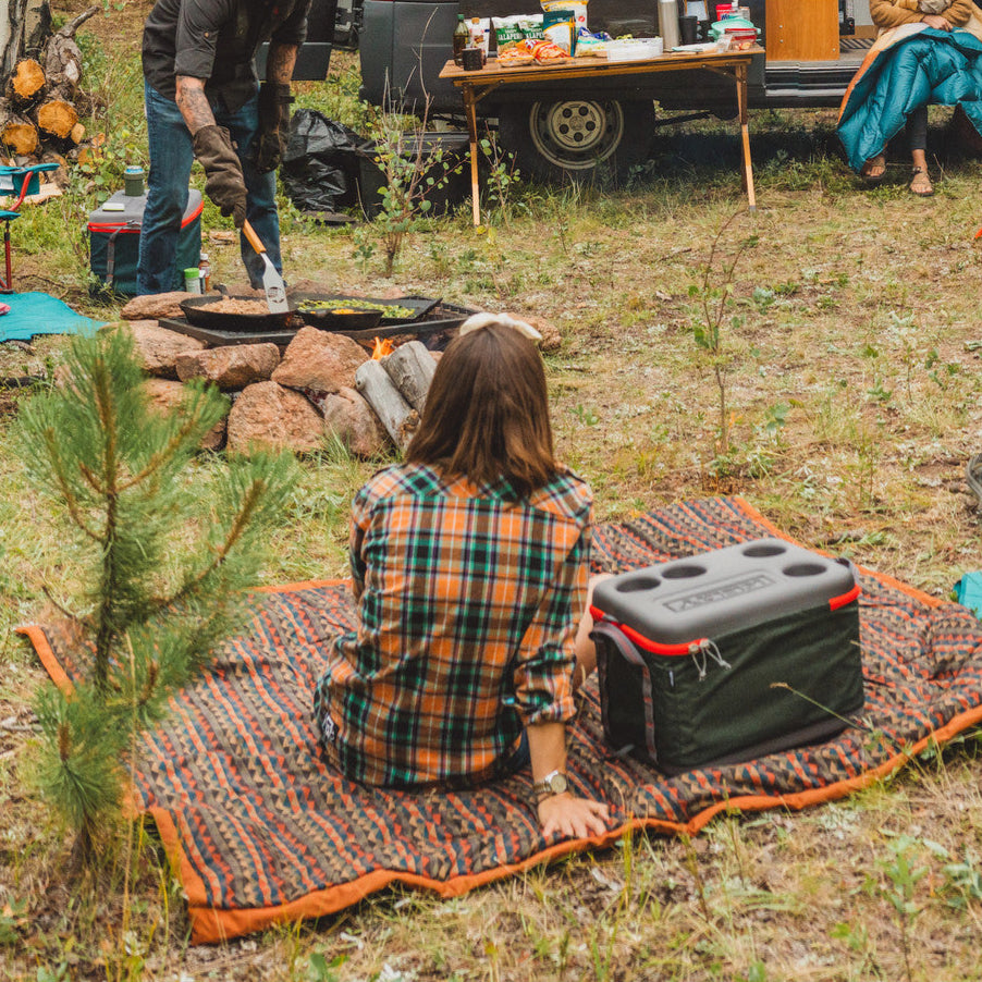 Woman at campsite sitting on Kelty Cordavan Blanket