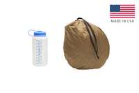 Kelty VariCom No Fly Zone USA bivy, shown packed inside of storage bag, bag standing on end next to 32 oz. water bottle